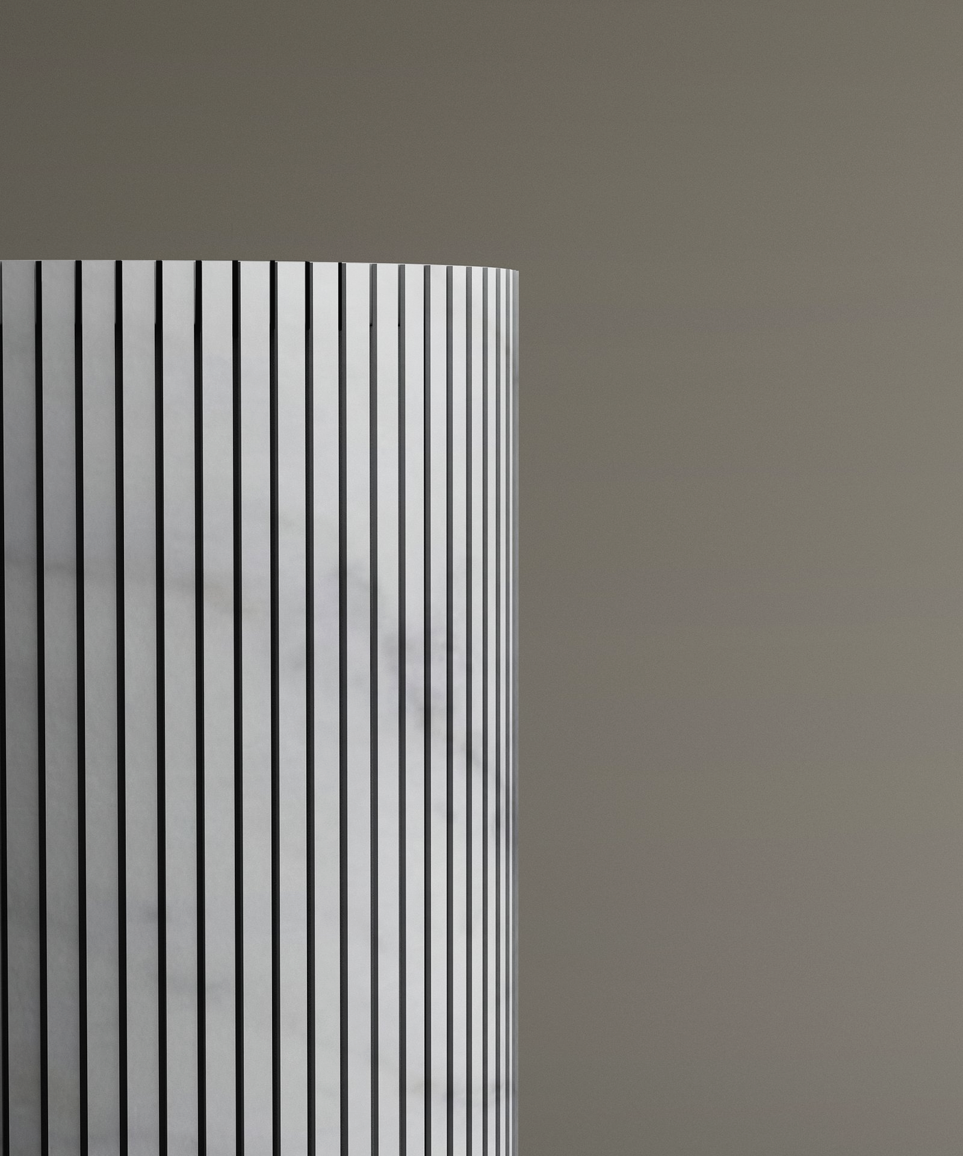 The left half of the TRAVERTABLE Carrara Round Fluted Marble Pedestal Vanity Sink, featuring vertical black-and-white stripes and fluted carving, stands against a plain light brown background.