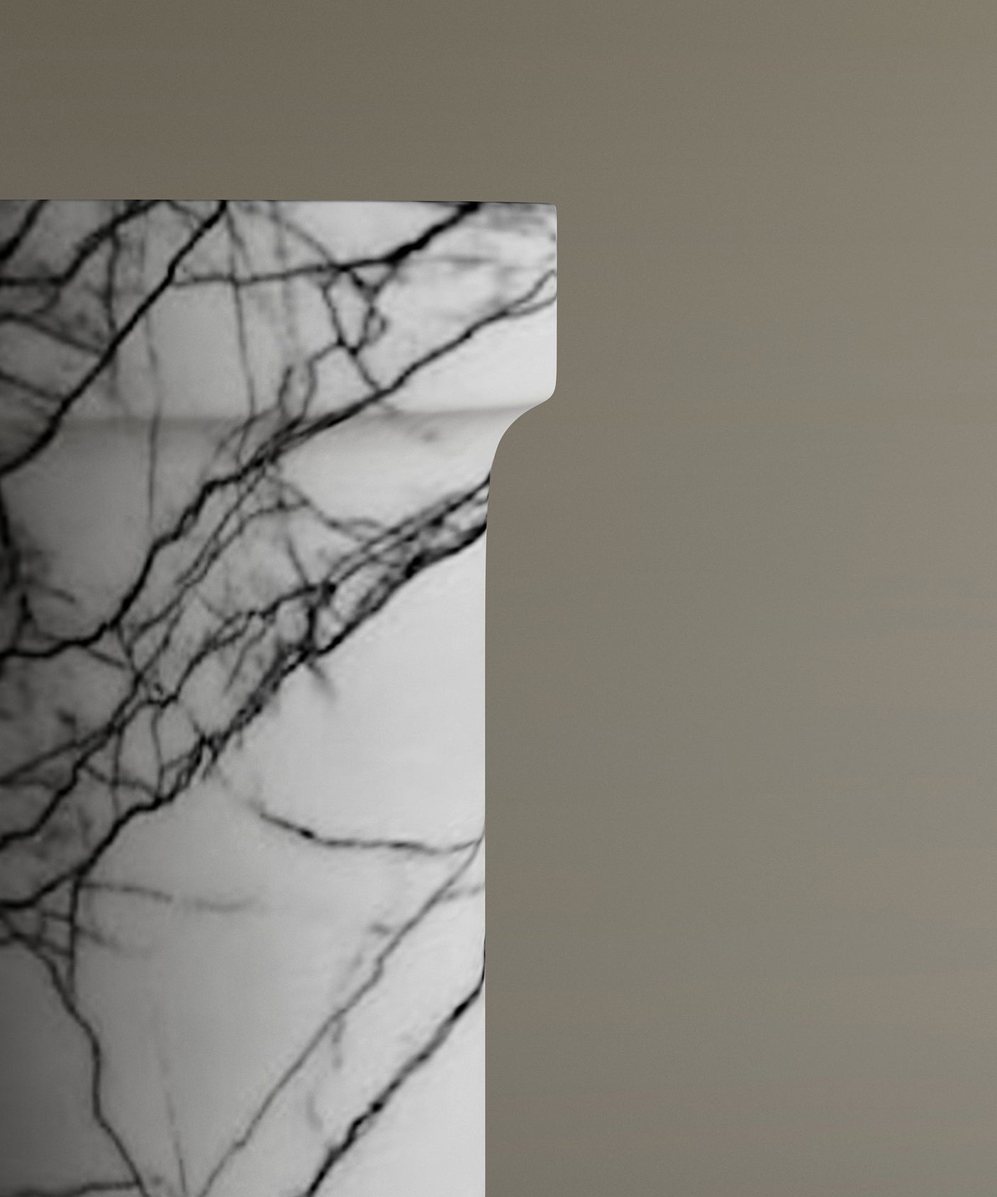 A close-up of the upper edge of the TRAVERTABLE Lilac Marble Pedestal Vanity Sink shows its rich, dark veining and unique texture set against a plain taupe background.