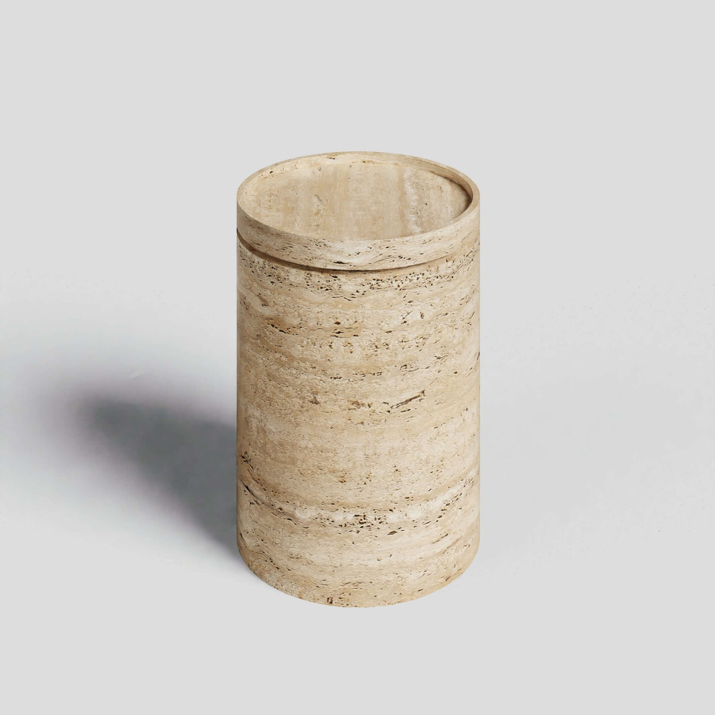 The Travertable Cycladic Secret Travertine End Table with Storage is a cylindrical, modern beige marble piece on a light gray background, featuring natural darker veins and a smooth surface reminiscent of natural light travertine.