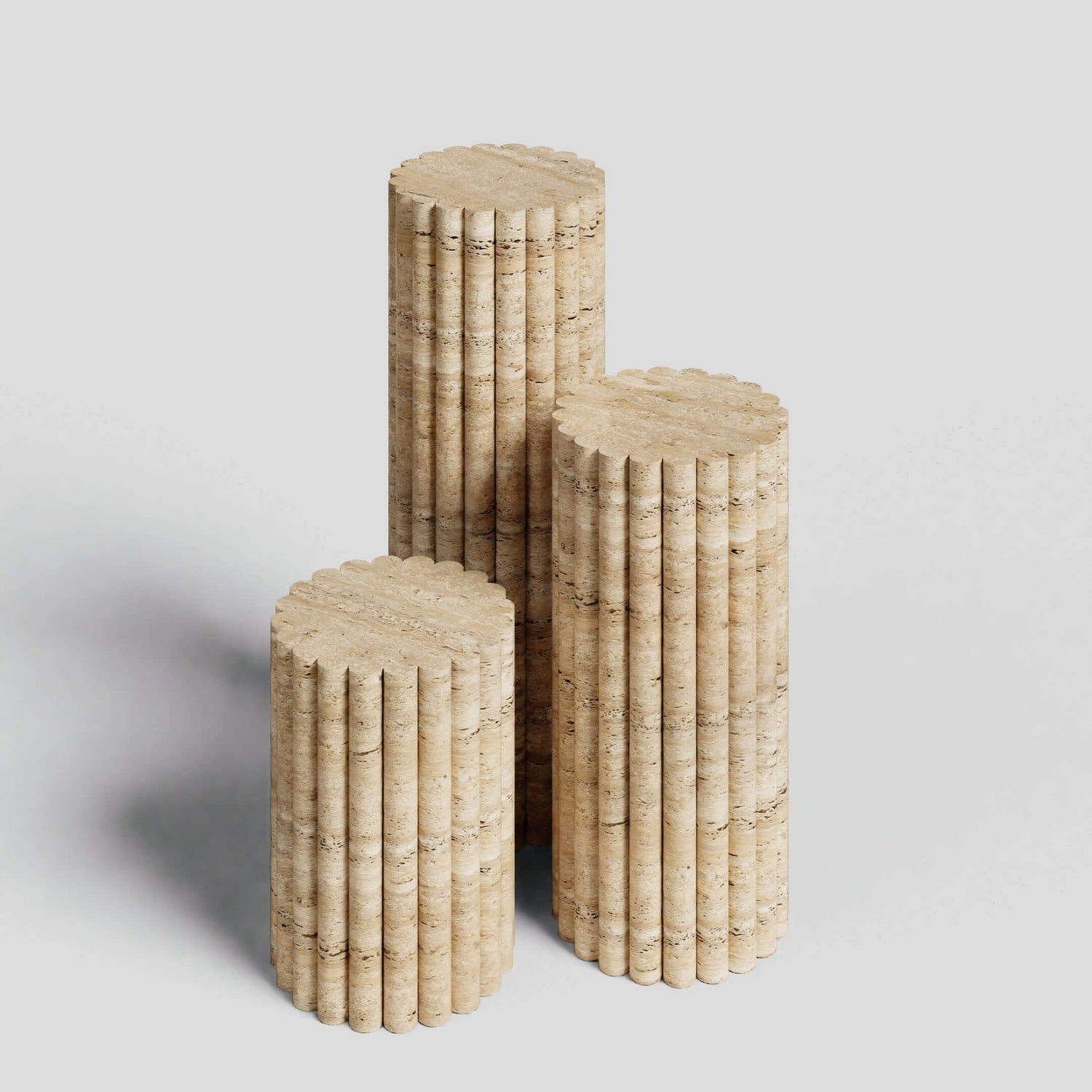 The Travertine Elegance Pillar Trio by Travertable features three beige, cylindrical columns with a stacked disk design and stone-like texture. These sculptural pieces add an artistic touch to any modern space when arranged against a plain background.