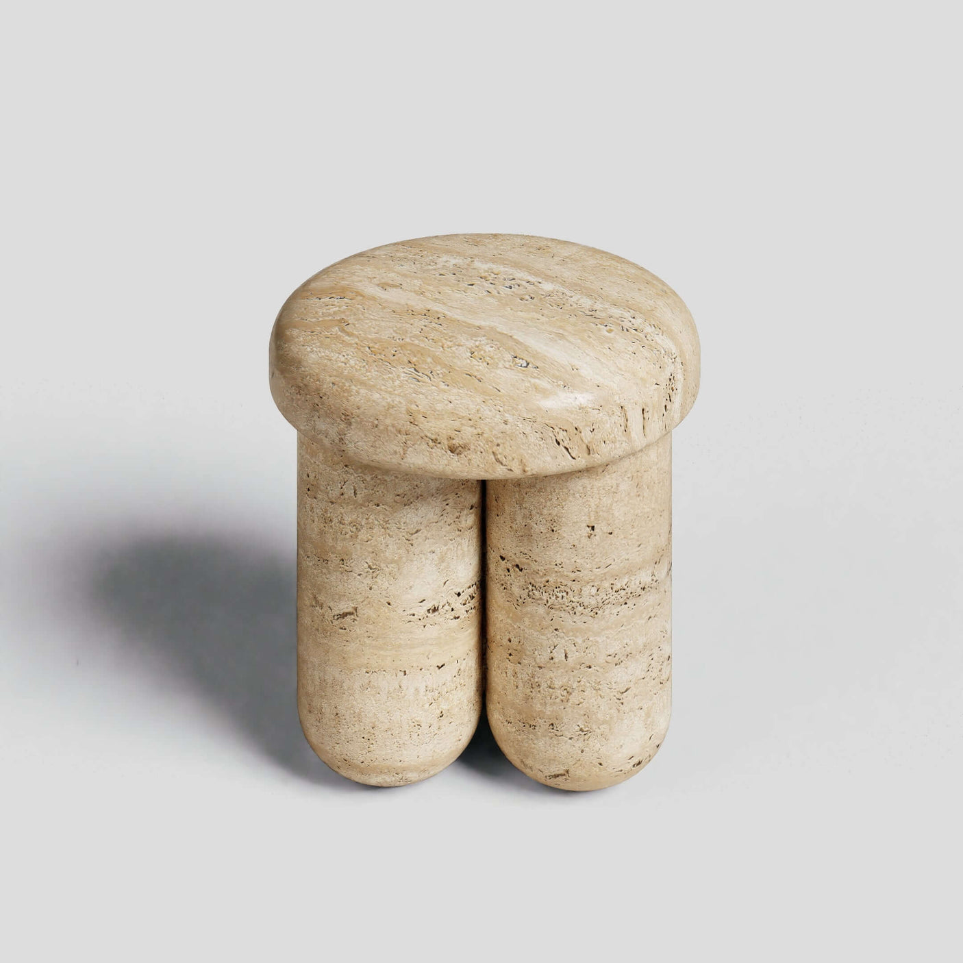 The Travertable Travertine Elegance Accent Table, a minimalist stool with a smooth, round top and two cylindrical legs, is crafted from beige travertine stone and set against a plain grey background.