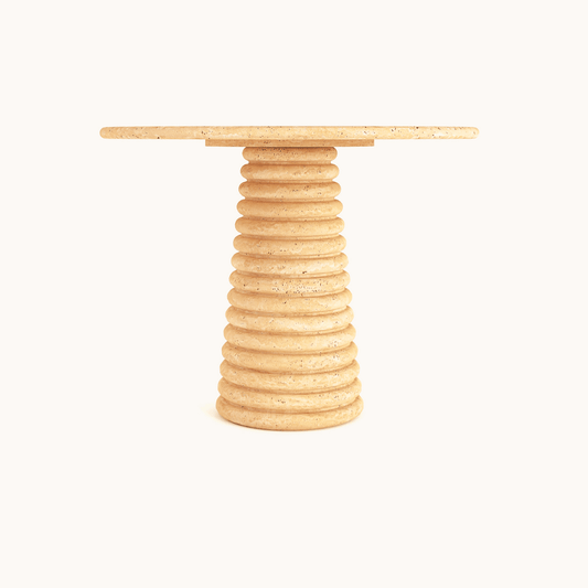 The Harmony Round Travertine Dining Table from Travertable is a simple, modern piece with a tan travertine top and spiral ribbed base. Its customizable to fit any style, and its elegant form is highlighted against a plain white background.