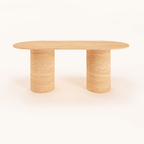 The Arcadia Dining Table by Travertable, an oval-shaped beige stone piece with a natural textured finish, features two cylindrical legs. Minimalistic and set against a white background, it can be customized to match any decor style.
