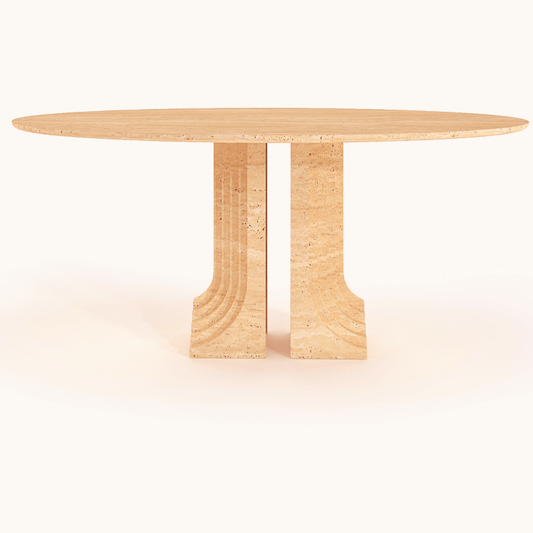 The Aurora Travertine Dining Table by Travertable is a round, beige table with a textured surface. It features a unique architectural base made of two vertical, curved slabs with a layered design, offering a minimalistic and modern aesthetic.