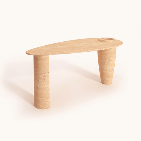 The Travertable Versatile Travertine Office and Dining Table is a light brown, uniquely shaped piece with two rounded legs. Its elongated, asymmetrical oval top has a circular indentation for a built-in vase, offering a minimalist and modern design for your space.