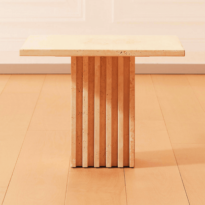 The Harmony Square Travertine Dining Table from Travertable features a light wooden rectangular top and a unique fluted pedestal base, elegantly placed on a warm-toned wood floor.