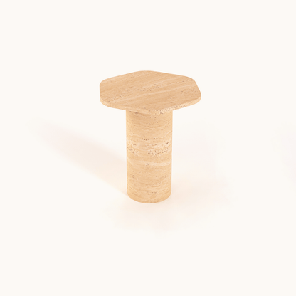 The Travertable Natural Beauty Travertine Side Table showcases an earthy elegance with its beige, hexagonal design and a handcrafted cylindrical base that mimics natural stone, all set against a plain white background.