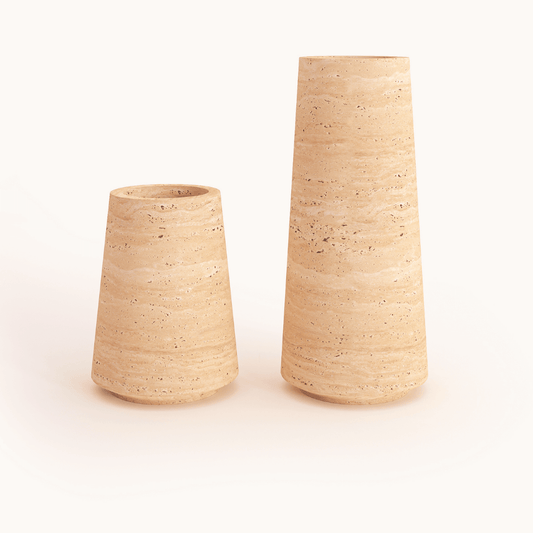 Two Classic Beige Travertine Vases by Travertable, featuring a speckled texture. The left is short and wide, and the right is tall and narrow. Both have a smooth matte finish, set against a plain white background.