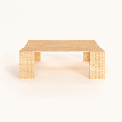 The Modern Rustic Travertine Coffee Table by Travertable, featuring block-style legs and a minimalist design, balances raw texture with refined form and showcases its natural beauty against a plain white background.