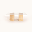 Introducing the Travertable Stone Horizon Coffee Table, a hand-sculpted masterpiece. This modern piece has a transparent glass top supported by dual semi-cylindrical beige stone bases, exuding natural beauty against its plain white background. Perfect for both modern and rustic interiors.