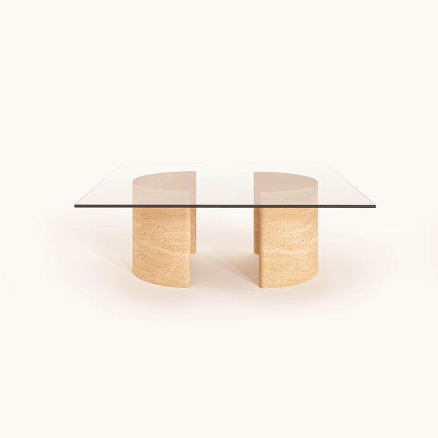 Introducing the Travertable Stone Horizon Coffee Table, a hand-sculpted masterpiece. This modern piece has a transparent glass top supported by dual semi-cylindrical beige stone bases, exuding natural beauty against its plain white background. Perfect for both modern and rustic interiors.