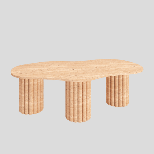 The Terra Solace Travertine Coffee Table by Travertable is a neutral-toned natural stone piece featuring a wavy, irregular top and three textured cylindrical legs that highlight natural beauty against a light gray background while showcasing expert craftsmanship.