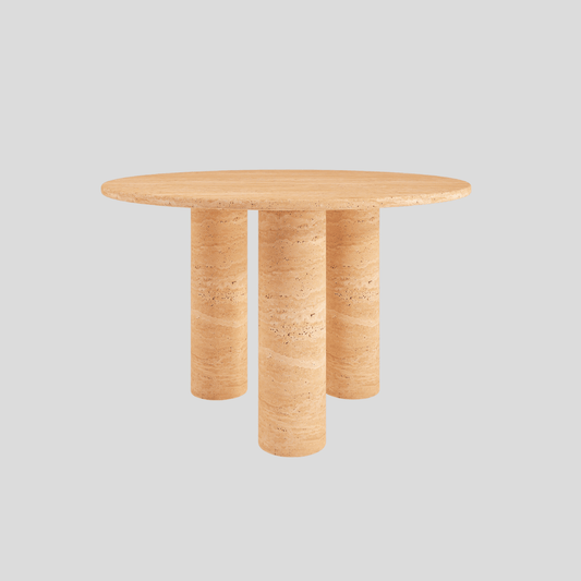 The Trio Round Travertine Dining Table by Travertable showcases a smooth beige travertine surface with three cylindrical legs, set elegantly against a plain gray background.