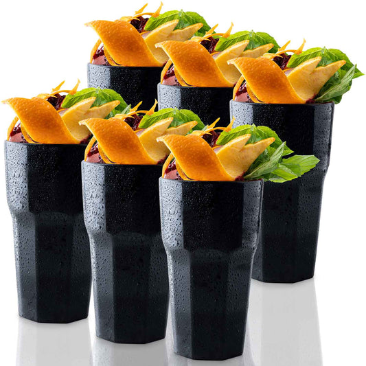 Six Mamaco Home Unbreakable Drinking Glasses, filled with an orange slice, mint leaves, and dark berry garnish, sit on a reflective surface. These reusable 11 oz black textured glasses showcase droplets of condensation on their durable exteriors.