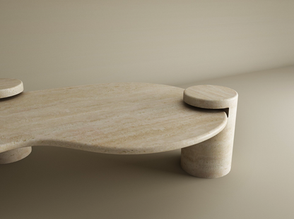 The Wavy Travertine Coffee Table with Cylindrical Base by TRAVERTABLE features sculptural curves, an organic flow, and a smooth travertine surface, shown here in beige against a matching background. Customizable to suit your modern space.