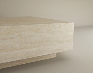 A close-up of the TRAVERTABLE Square Travertine Coffee Table with Hidden Base showcases its hand-finished surface, natural patterns, and minimalist elegance—an understated, customizable piece set against a plain background.