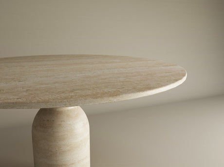 A close-up view of the TRAVERTABLE Oval Travertine Dining Table with a round sculptural center base. The polished, light beige surface features natural stone patterns, highlighting this customizable, organic travertine form against a neutral backdrop.