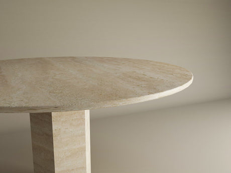 The TRAVERTABLE Oval Travertine Dining Table features a light beige stone top and a hexagonal center base, blending geometric design with timeless elegance. Customizable and crafted with enduring quality, it stands out against a neutral background.