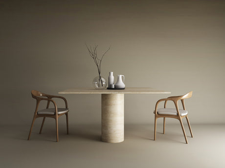 A minimalist dining setup featuring TRAVERTABLEs Square Travertine Dining Table with Cylindrical Center Base in pure stone, paired with two wooden chairs with white cushions and vases, set against a plain beige background.