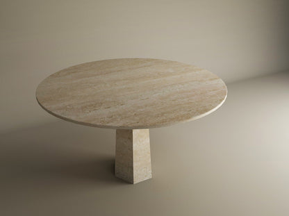 The TRAVERTABLE Oval Travertine Dining Table features a smooth travertine stone top and a distinctive rockcone center pedestal base, shown against a plain beige background. Customizable to suit your dining space.