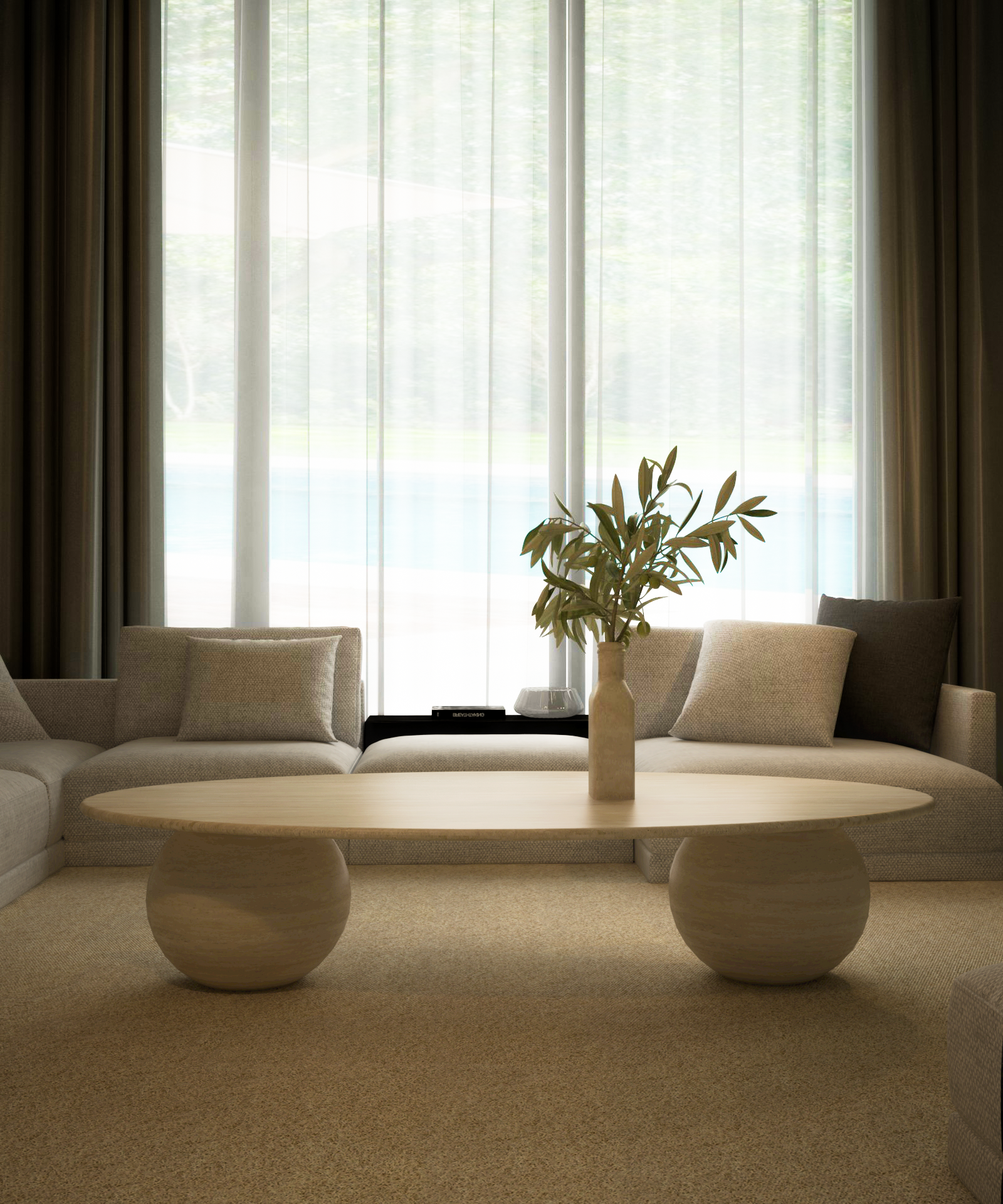A modern living room featuring TRAVERTABLEs customizable Ellipse Travertine Coffee Table with a sculptural stone ball base, a vase of leafy branches, two cream sofas with neutral cushions, and sheer curtains over a tall window with an outdoor view.