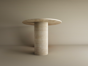 The Ellips Travertine Dining Table by TRAVERTABLE features a minimalist, round, light stone top and a fluted solid travertine base, shown against a plain beige background. This customizable dining table blends elegance with natural texture.