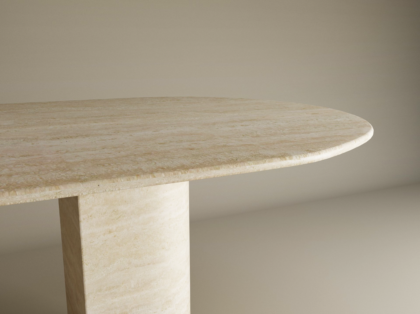 A close-up of the TRAVERTABLE Oval Travertine Dining Table shows its beige natural stone top with rounded edges and a sloped pedestal base, highlighting its heirloom elegance against a plain light background. Customizable options available.