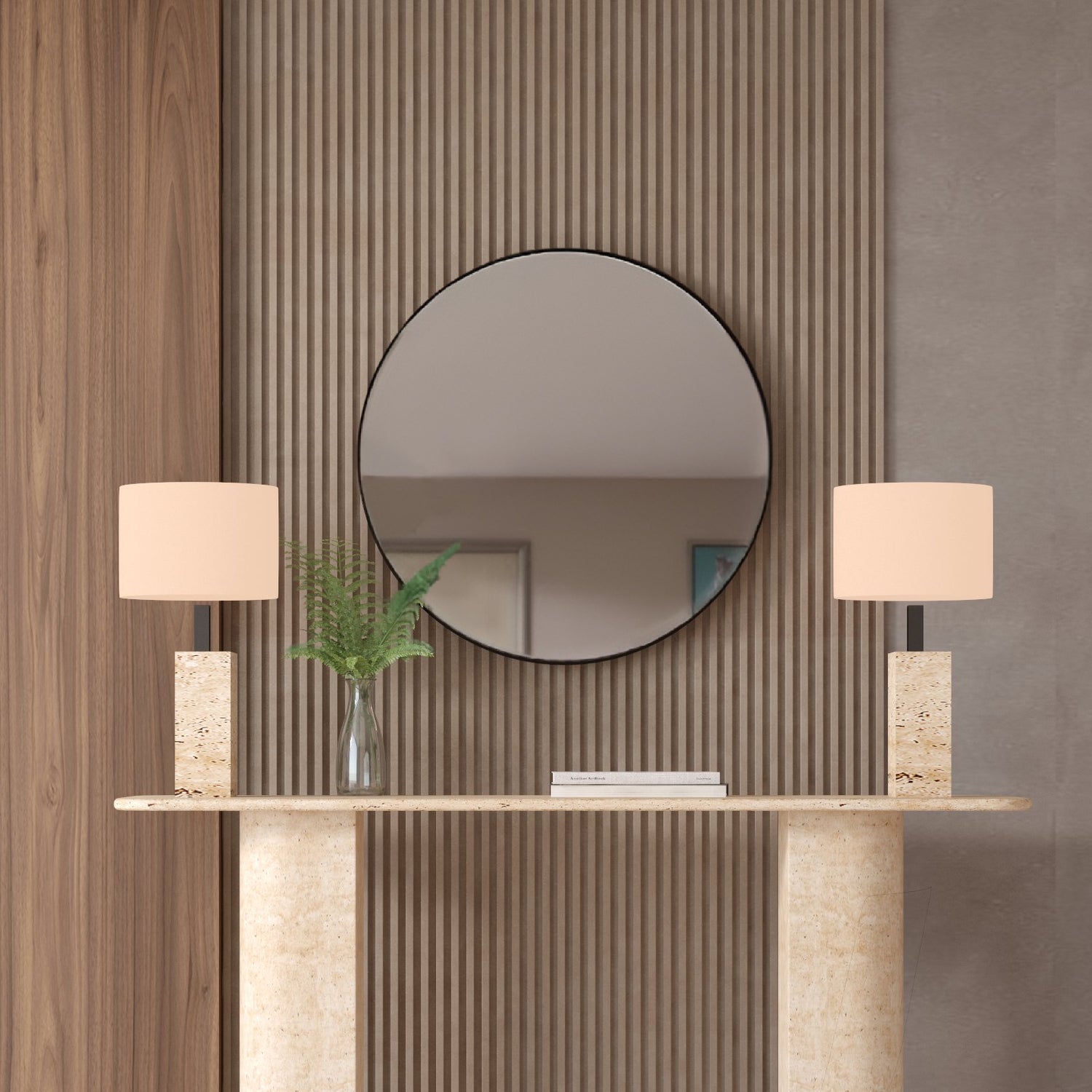 A TRAVERTABLE Rectangular Travertine Console Table with Sloped Pedestal Base, flanked by matching lamps and a glass vase of ferns, sits against a textured wall beneath a round mirror reflecting the room’s neutral decor.