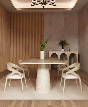 A modern dining room featuring the TRAVERTABLE Rectangular Travertine Dining Table with a conical pedestal base, four light wood chairs, a white vase with green leaves, a sideboard with decor, and beige walls with vertical wood paneling.
