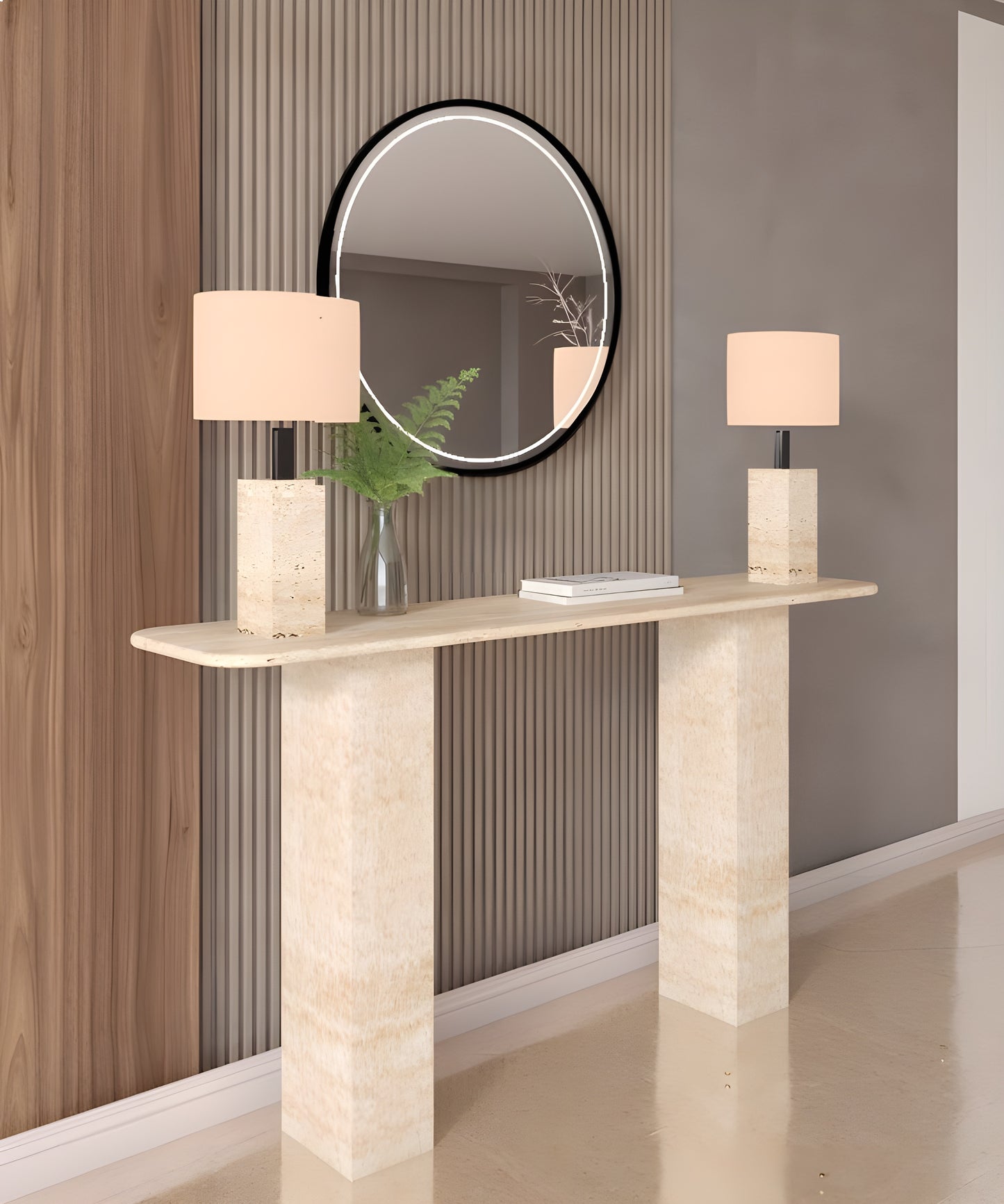 The TRAVERTABLE Rectangular Travertine Console Table with Pedestal Base displays two square lamps and a glass vase of greenery, set below a round mirror on a backdrop of vertical wood paneling.