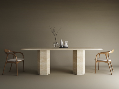 A minimalist dining setup showcases the TRAVERTABLE Rectangular Travertine Dining Table with a hexagonal organic stone base, paired with two cushioned wooden chairs and simple vase decor set against a neutral beige backdrop.