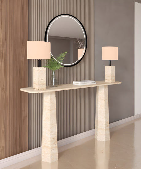 A Rectangular Travertine Console Table with Tapered Round Base by TRAVERTABLE displays two matching lamps, a vase with greenery, and a book. Placed against vertical wall paneling, it sits beneath a round mirror reflecting the room.