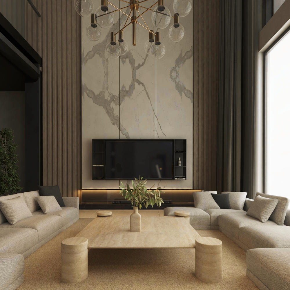 A modern living room with beige sofas in a U-shape around the TRAVERTABLE Square Travertine Coffee Table with Cylindrical Legs. A plant sits on the table. The space features a TV on a marble accent wall, tall windows, neutral tones, and a geometric chandelier above.