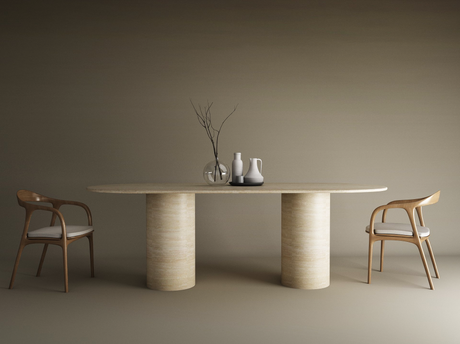 A minimalist dining setup featuring the TRAVERTABLE Oval Travertine Dining Table with Smooth Cylinder Base, two wooden chairs with white cushions, and simple vases—one holding bare branches—set against a plain taupe background.