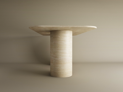The TRAVERTABLE Rectangular Travertine Dining Table features a smooth, pure travertine stone cylinder base and a flat rectangular tabletop, shown against a plain beige background. The table is fully customizable for your dining space.