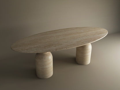 The Ellips Travertine Dining Table by TRAVERTABLE features a customizable natural travertine stone top with a sculptural round organic base, all in a matching beige marbled finish, set against a neutral background.
