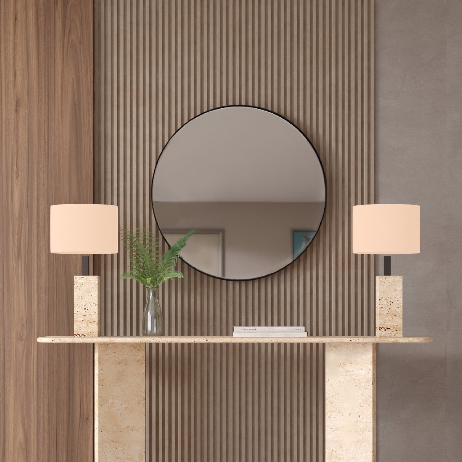 The TRAVERTABLE Rectangular Travertine Console Table with Split-V Pedestal Base stands before a wood and gray paneled wall, accented by two beige lamps, a vase of green leaves, and a round mirror above for modern flair.