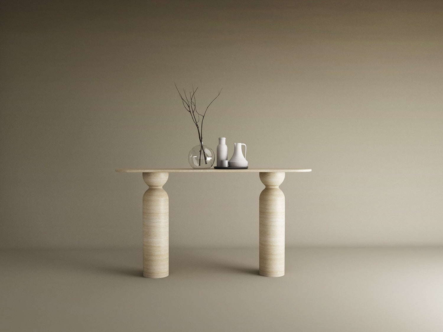 The Ovale Travertine Console Table by TRAVERTABLE, featuring a sculptural round base in organic travertine stone, displays a thin branch in a glass vase, a white pitcher, and jug against a beige backdrop—an understated statement piece.