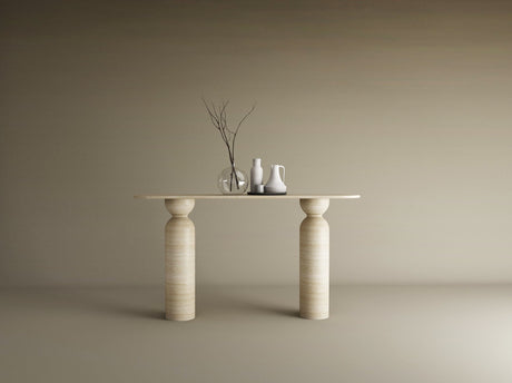 The Ovale Travertine Console Table by TRAVERTABLE, featuring a sculptural round base in organic travertine stone, displays a thin branch in a glass vase, a white pitcher, and jug against a beige backdrop—an understated statement piece.