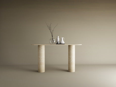 The TRAVERTABLE Ovale Travertine Console Table features a pure travertine stone base with two smooth cylindrical legs, displaying three vases—one clear with bare branches and two opaque white—set against a plain beige background.