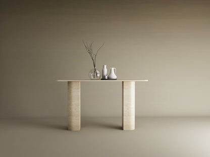 The TRAVERTABLE Rectangular Travertine Console Table with Sloped Pedestal Base in natural stone displays a glass vase with bare branches and two ceramic pitchers, set against a plain beige background.