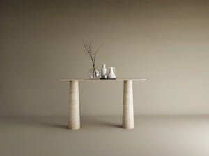 The Ovale Travertine Console Table by TRAVERTABLE features an organic travertine stone top and conical pedestal base. Three ceramic vases—one transparent, two opaque—with bare branches sit against a plain beige background.