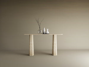 The TRAVERTABLE Rectangular Travertine Console Table with a solid, tapered round base displays a glass vase and ceramic vessels in minimalist beige, set against a plain background. This customizable piece offers contemporary elegance.