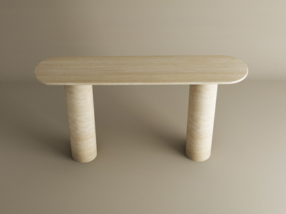 The TRAVERTABLE Ovale Travertine Console Table features an oval stone top and two smooth cylindrical pure travertine bases, combining minimalist modern style with customization options, shown against a plain beige background.