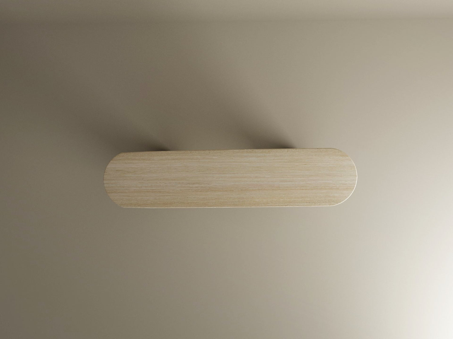 The Ovale Travertine Console Table by TRAVERTABLE, featuring a pure travertine stone base and smooth cylinder support, is displayed on a beige wall and viewed from above, casting a subtle shadow. Customization options available.