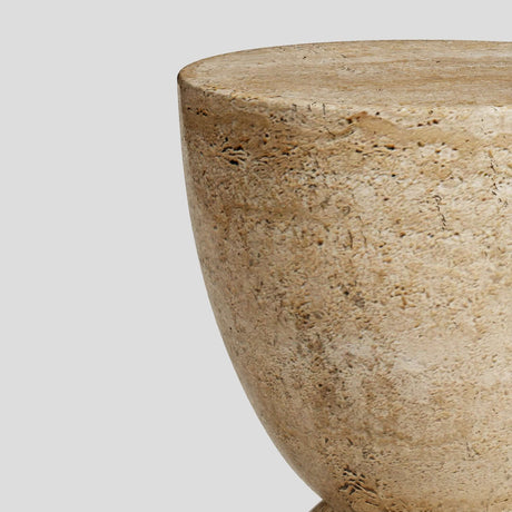 A close-up of the beige, rounded top half of the Eda Beige Travertine Sphere Table by Travertable. The elegant, minimalist solid stone piece sits against a plain gray background, showcasing its travertine-inspired design.