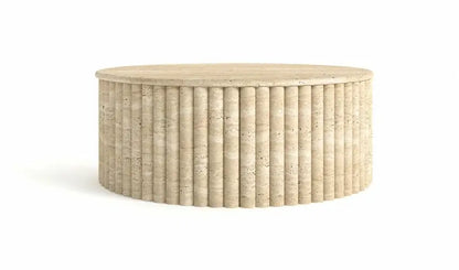 The Alpine Oasis Travertine Coffee Table by Travertable is a round, beige table with a fluted, cylindrical base and smooth top, resembling natural stone. Its vertical ridges and textured design offer a modern look that complements elegant interiors against a plain white backdrop.