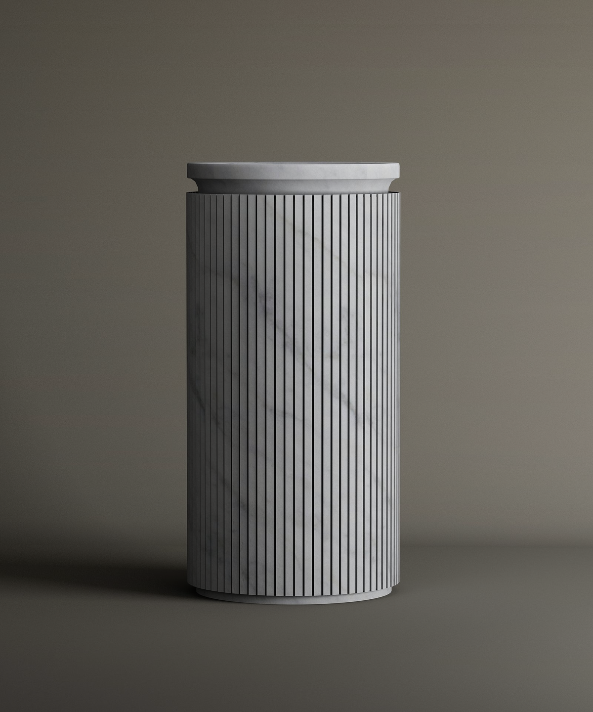 The TRAVERTABLE Carrara Round Marble Pedestal Vanity Sink features a tall, cylindrical form with vertical grooves and smooth Carrara marble surface, highlighted by subtle gray veining against a neutral background.