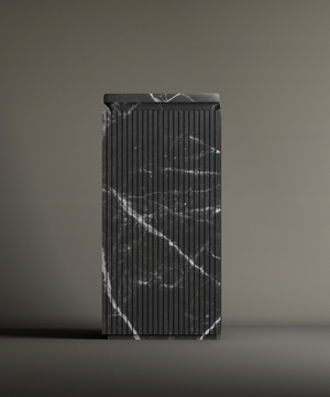 The TRAVERTABLE Nero Marquina Square Marble Pedestal Vanity Sink features vertical grooves and dramatic white veining, standing tall against a simple, neutral background.