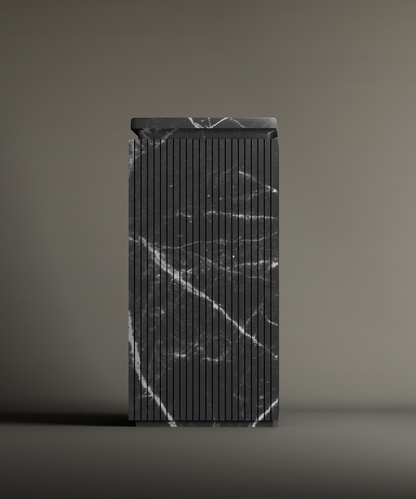 The TRAVERTABLE Nero Marquina Square Marble Pedestal Vanity Sink features vertical grooves and dramatic white veining, standing tall against a simple, neutral background.